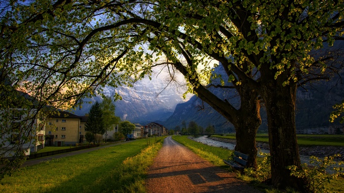 Dirt road leading to mountains with houses and trees