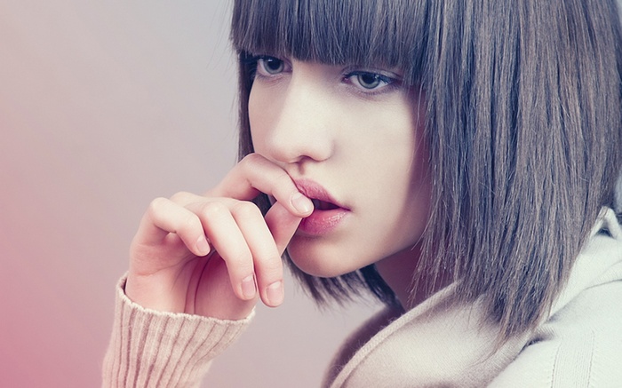 Woman with bangs and finger on lips