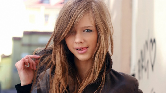 Young woman with long hair sticking out her tongue