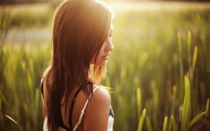Woman with long brown hair in a field at sunset