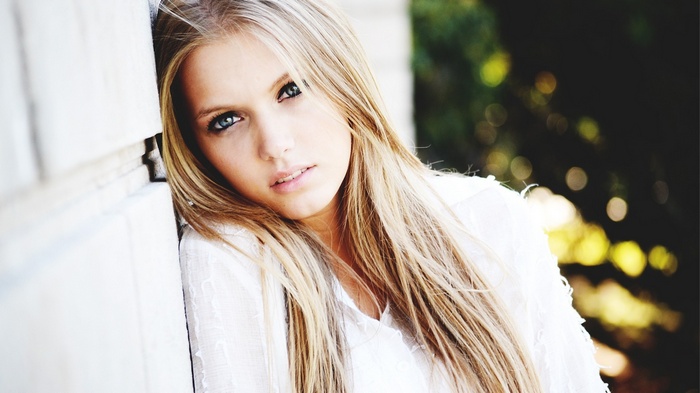Portrait of a blonde woman leaning against a wall
