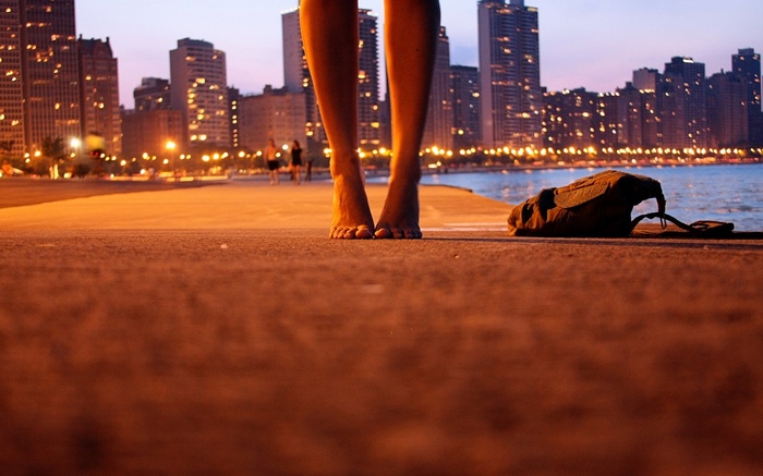 Barefoot woman's legs in a cityscape at dusk