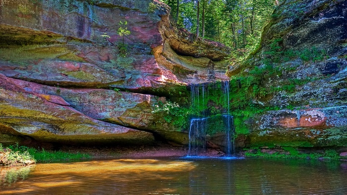 Waterfall cascading into a pool near colorful rock formations
