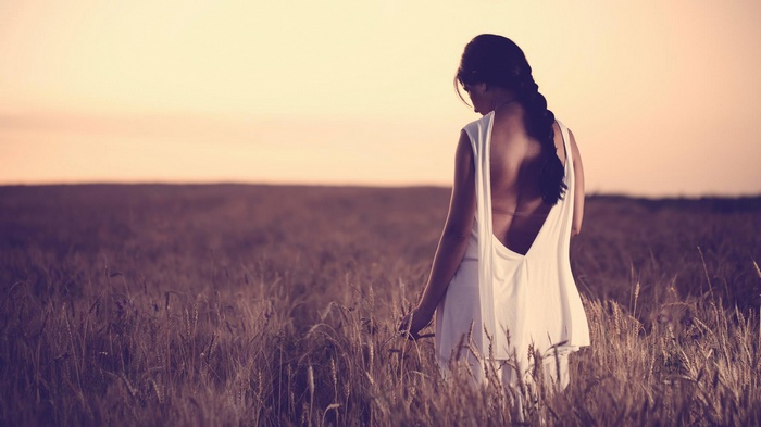 Woman in white dress in a wheat field at sunset