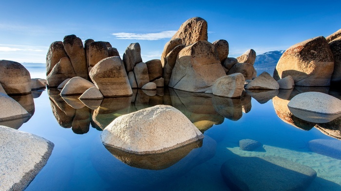 Rocks in clear blue water with mountain background