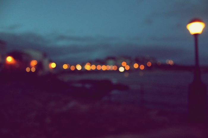 Bokeh lights of a city at dusk with a lamppost