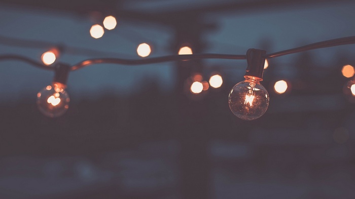 String of glowing light bulbs at dusk