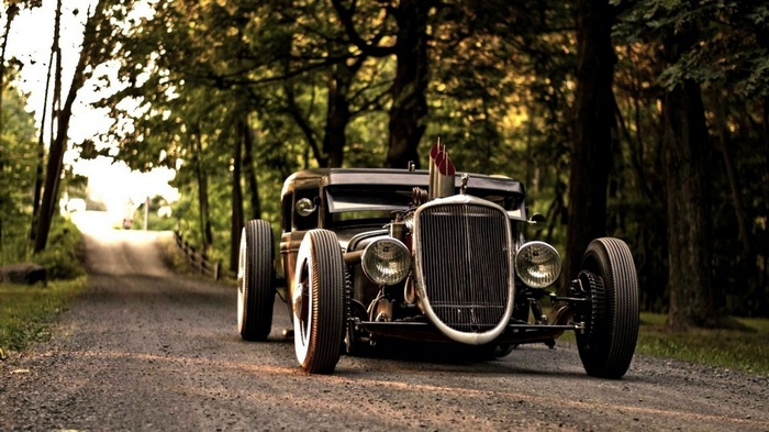 Rat Rod car on a dirt road in a forest