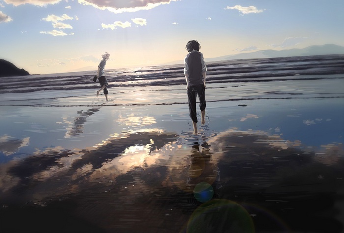 Two boys walking on a beach at sunset