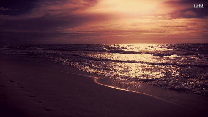 Beach at sunset with waves and footprints