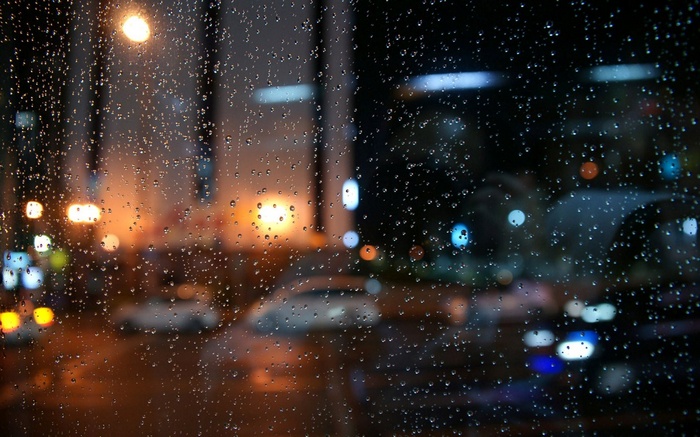 Raindrops on glass with bokeh city lights at night