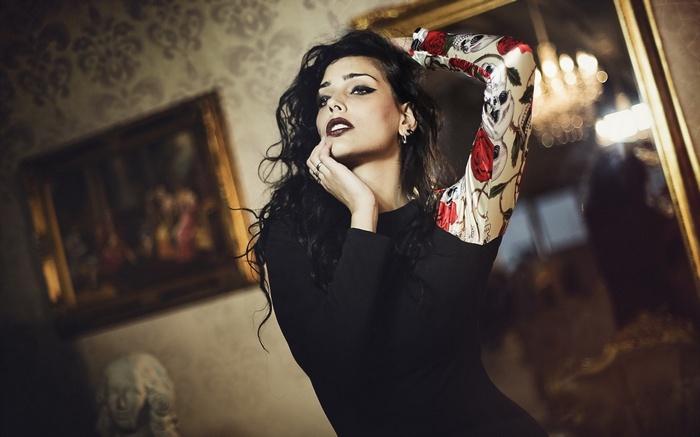 Woman with dark hair and tattoos in a room
