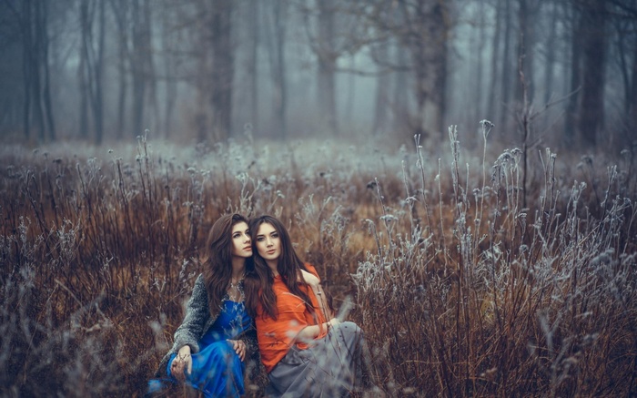 Two women sitting in a frosty forest field