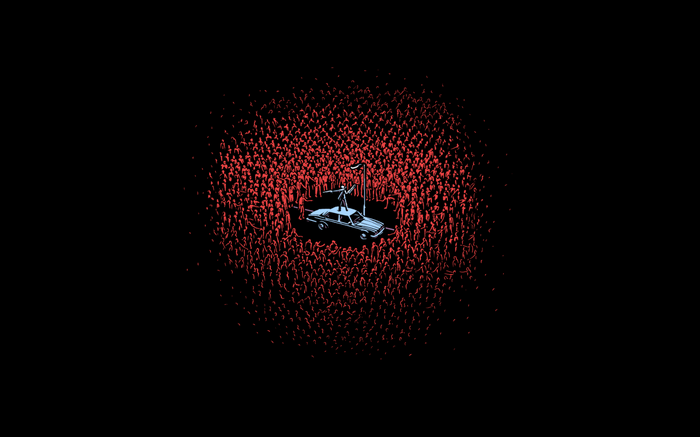 A person stands on a car surrounded by a crowd