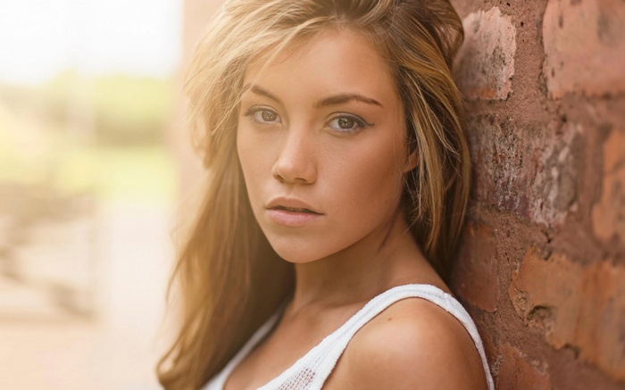 Woman leaning against a brick wall