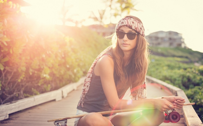 Woman with sunglasses and bandana on skateboard