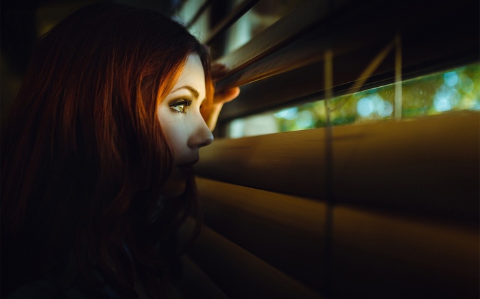 Redhead woman looking through blinds