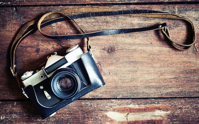 Vintage camera with leather case on wooden surface