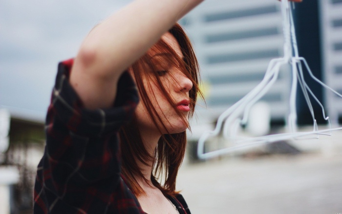 Redhead woman with eyes closed holding hangers