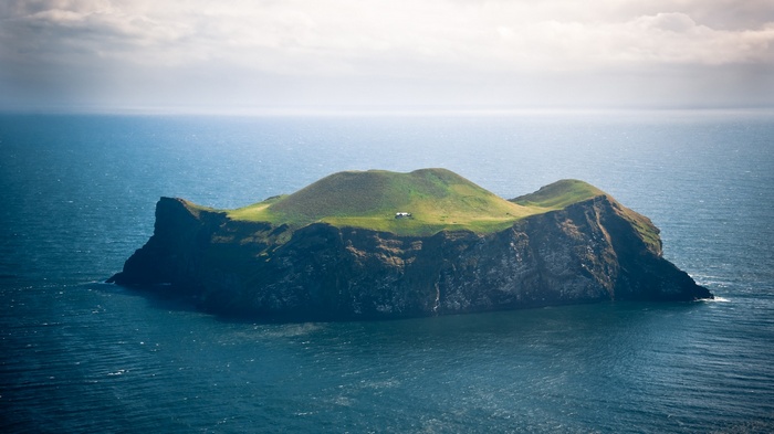 A small house on a grassy island in Vestmannaeyjar, Iceland