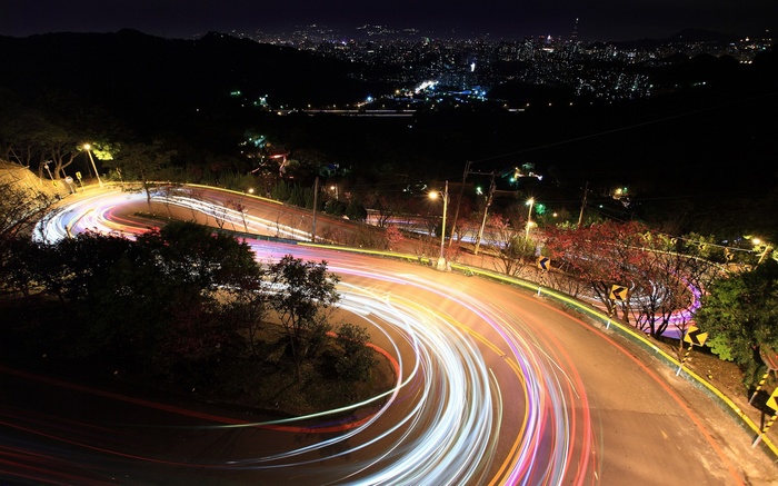 Night road with light trails and city lights