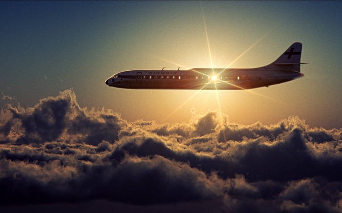 Finnair airplane flying through clouds at sunset with lens flare