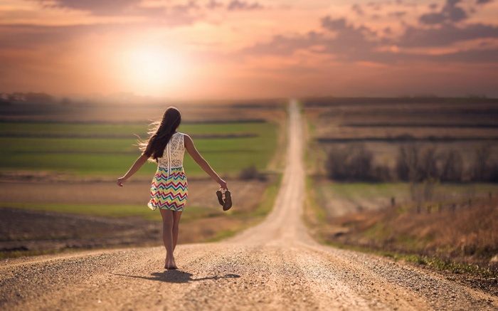 Woman walking barefoot on a road in Nebraska at sunset