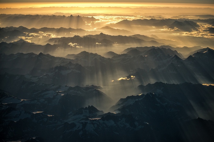 Sunlight beams through mountain ranges at sunset