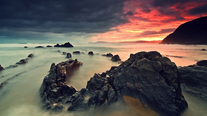 Dramatic sunset over rocky coast with ocean waves