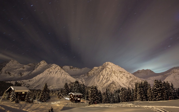 Snowy mountains and cabins under a starry night sky