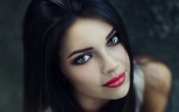 Woman with dark hair and green eyes wearing lipstick