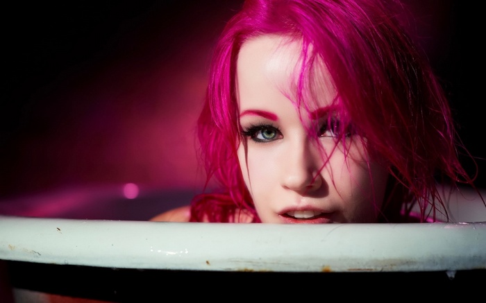 Woman with pink hair in a bathtub