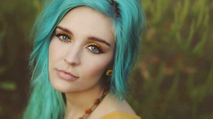 Woman with teal hair and yellow eyeshadow outdoors