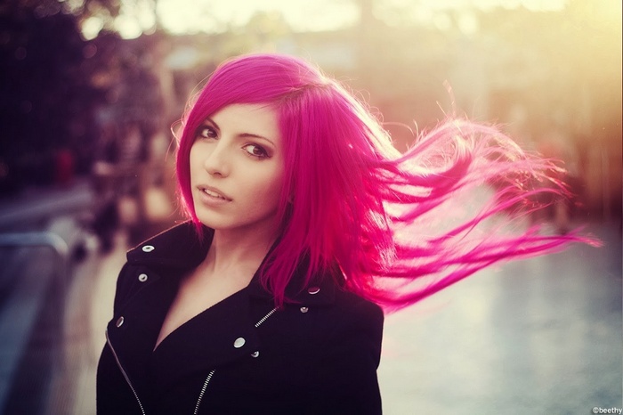 Woman with pink hair wearing a black jacket outdoors