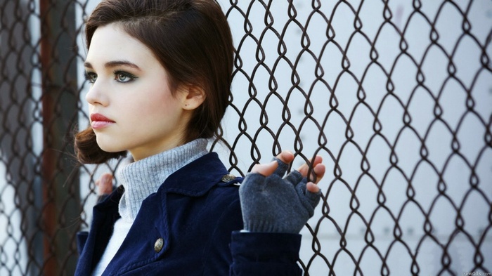 India Eisley by a chain-link fence