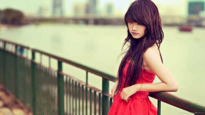 Woman in red dress by a railing overlooking water