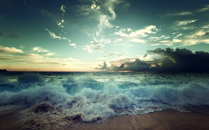 Waves crashing on a beach at sunset