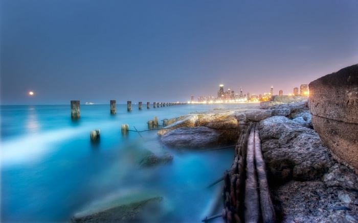 Chicago skyline at night over Lake Michigan with rocky shore