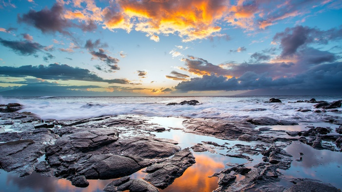 Sunset over the ocean with rocky coast and clouds