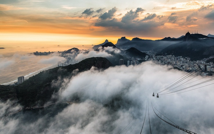 Cable cars over Rio de Janeiro mountains with clouds at sunset