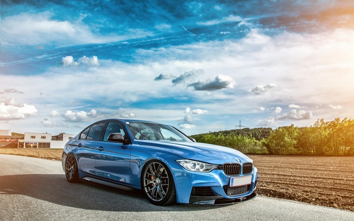 Blue BMW car on a road with clouds