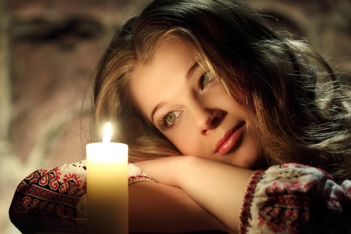 Young woman in traditional Ukrainian clothing by candlelight