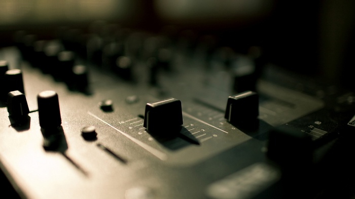 Close-up of a DJ mixing console with knobs and faders