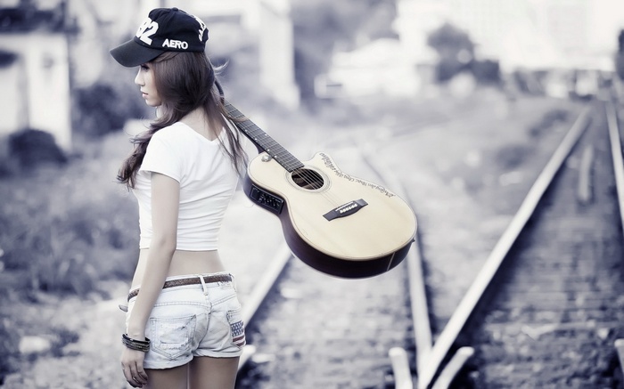 Woman with guitar on railway tracks