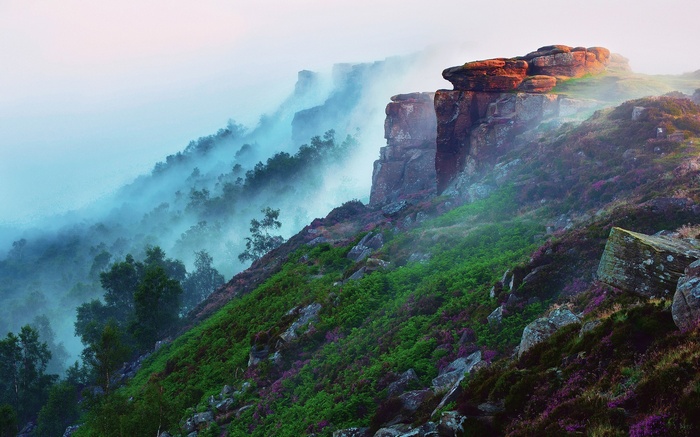 Misty mountainside with rocky outcrops and heather