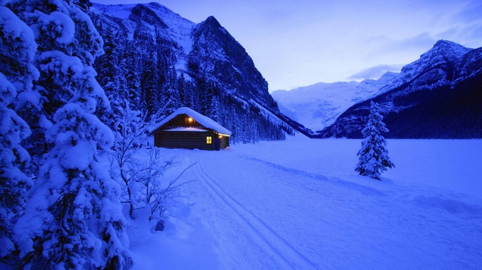 Snowy cabin in a mountain valley at dusk