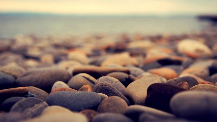 Close-up of smooth stones on a beach with the ocean in the background