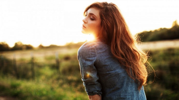 Woman with long red hair in a denim shirt outdoors