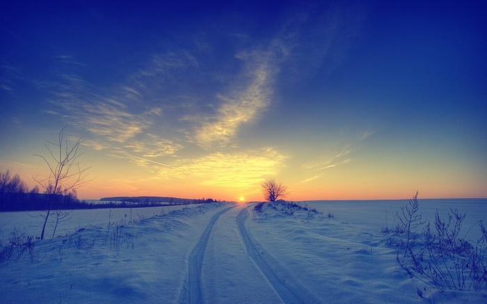 Winter landscape with a snowy road at sunset