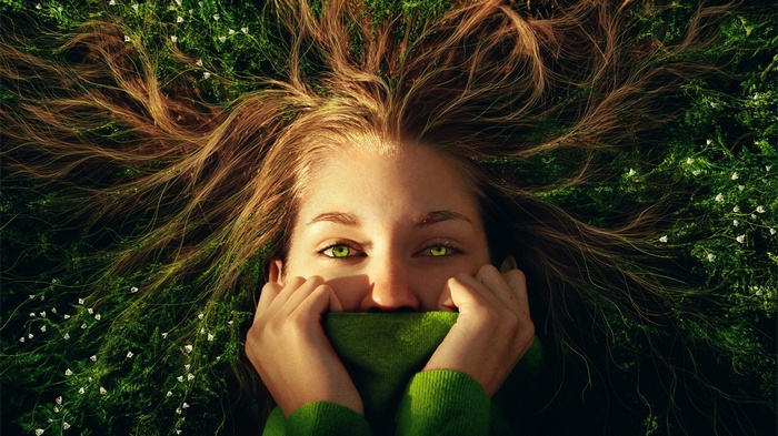Woman with green eyes lying in grass